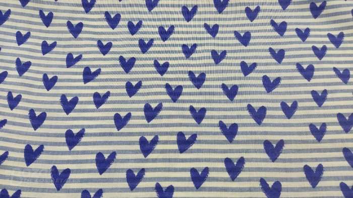 Popelín de algodón con corazones azules sobre fondo del líneas blancas y azules